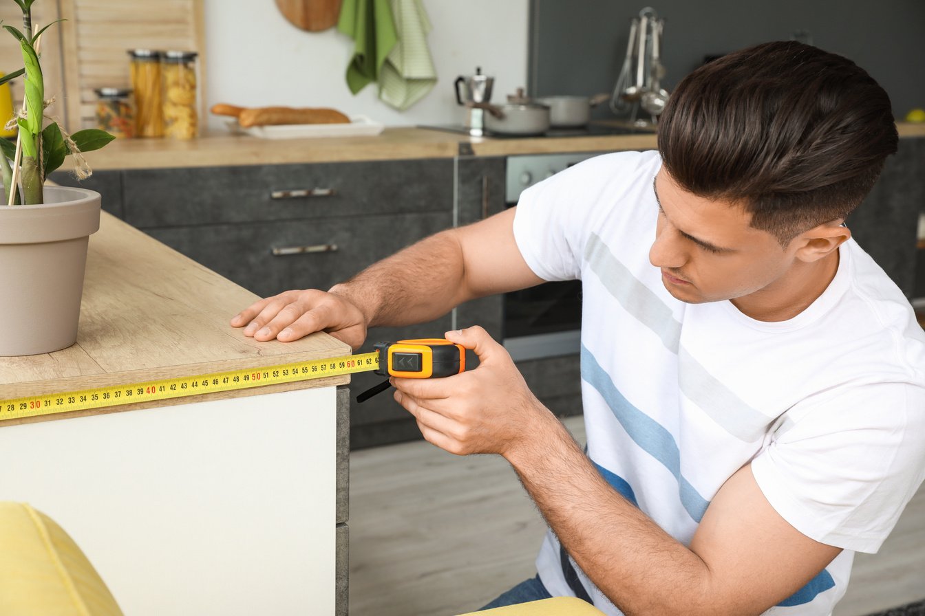 Man Taking Measures of Table in Kitchen